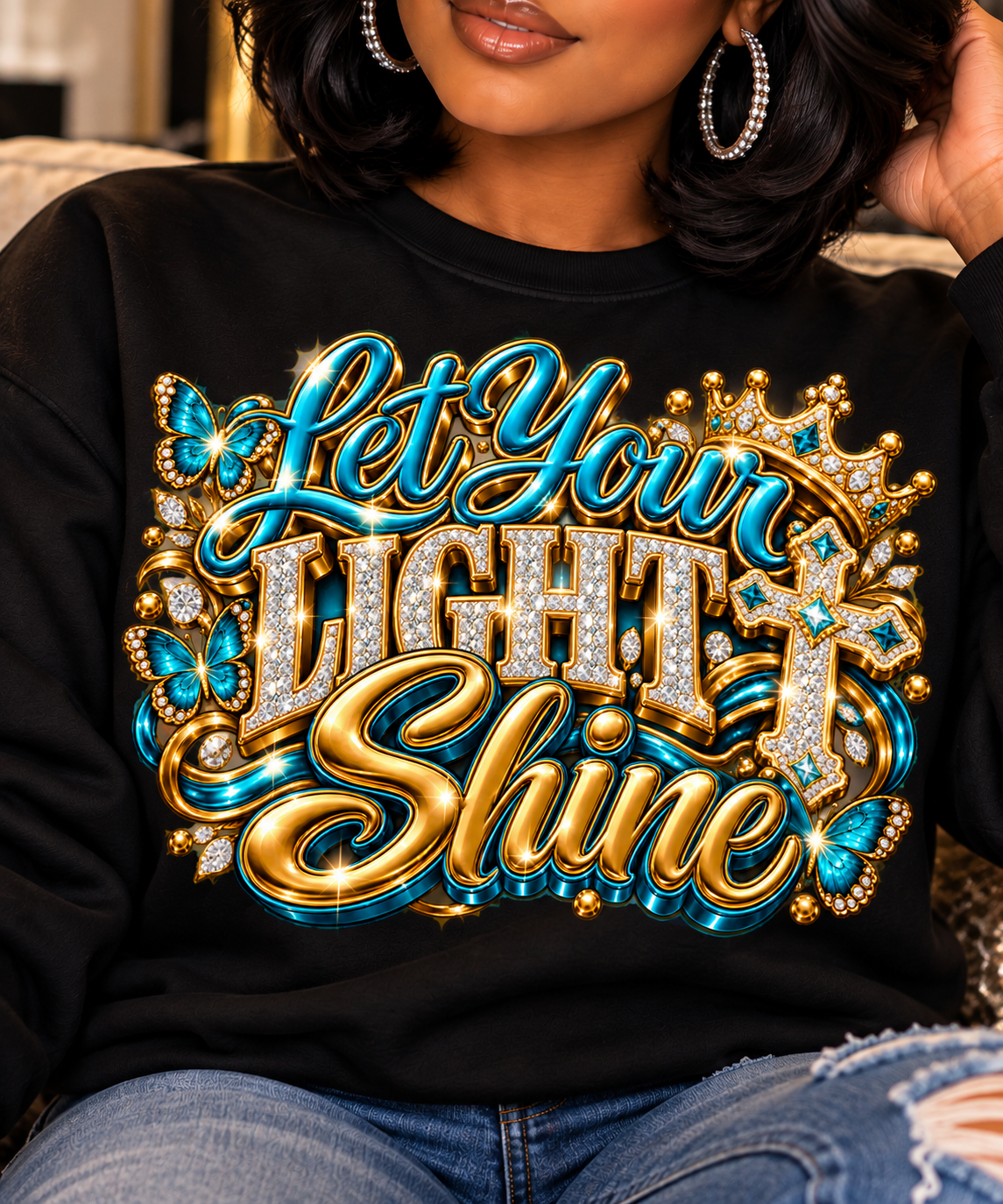 Let Your Light Shine design in turquoise and gold on a black sweatshirt, close-up